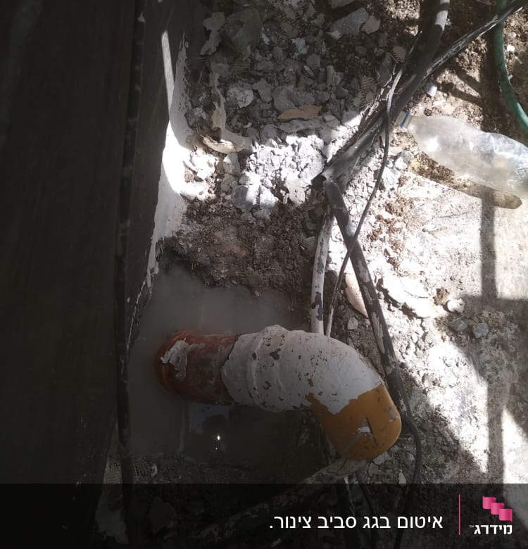 צינור כתום עם איטום לבן בתוך בטון שבור